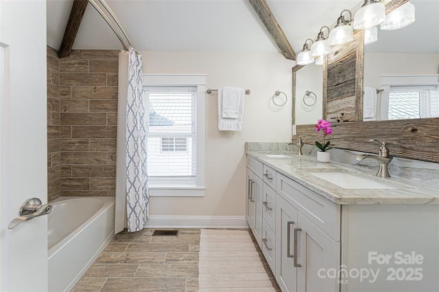 full bathroom featuring beam ceiling, a healthy amount of sunlight, and a sink