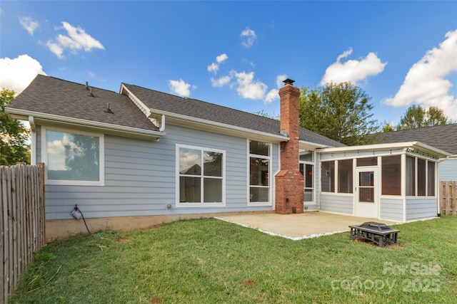 rear view of house featuring a patio, fence, an outdoor fire pit, a yard, and a sunroom