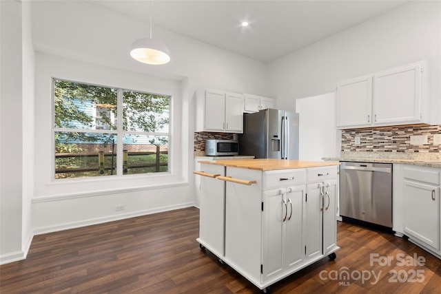 kitchen featuring a kitchen island, dark wood-type flooring, appliances with stainless steel finishes, white cabinetry, and tasteful backsplash