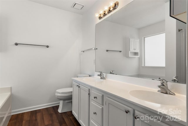 bathroom with a bath, toilet, wood finished floors, and a sink