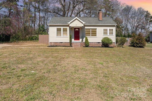 view of front of property with a front lawn, fence, roof with shingles, and crawl space