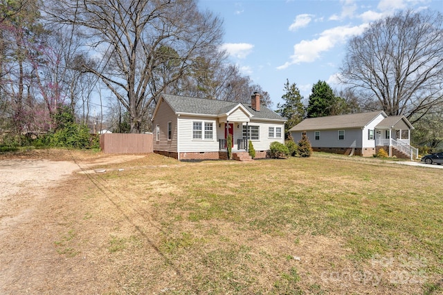 view of front of house with crawl space, a chimney, a front lawn, and fence