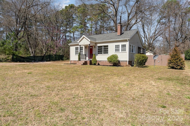 view of front of property with a shingled roof, a front lawn, fence, a chimney, and crawl space