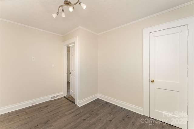 spare room with crown molding, dark wood-style floors, visible vents, and baseboards