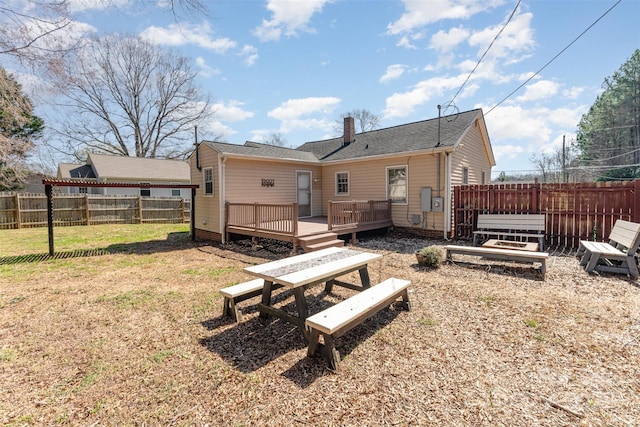 rear view of house featuring a wooden deck, a vegetable garden, a fenced backyard, a chimney, and a lawn