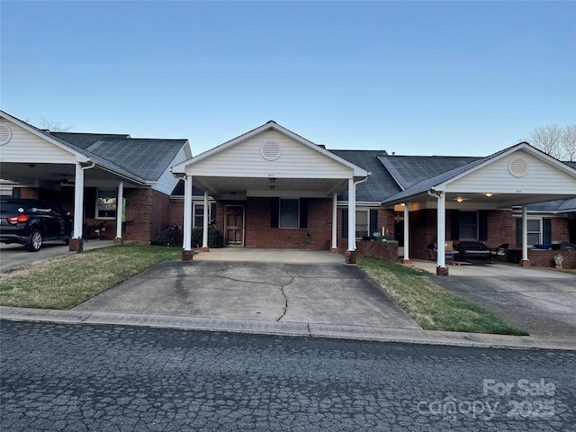 single story home with a front lawn, an attached carport, concrete driveway, and brick siding