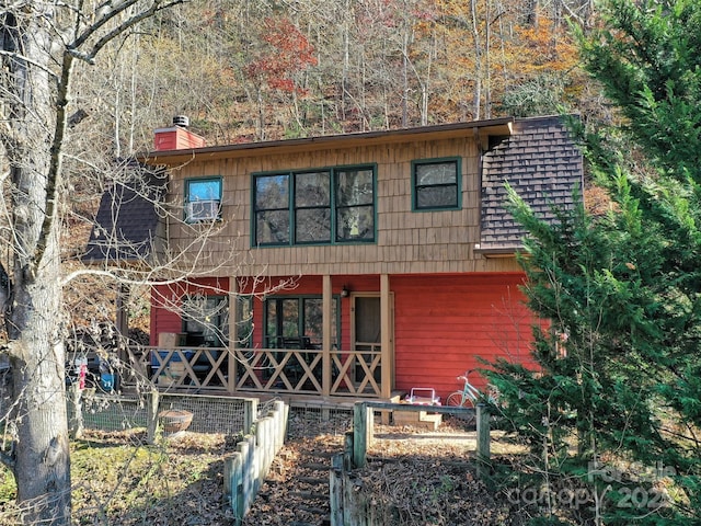 view of front of house with fence, roof with shingles, and a chimney