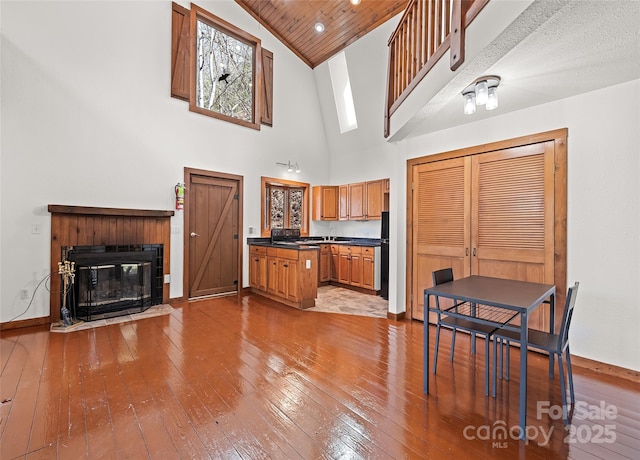 kitchen featuring hardwood / wood-style floors, dark countertops, a fireplace with flush hearth, and baseboards