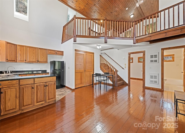 kitchen featuring dark countertops, wooden ceiling, freestanding refrigerator, and a towering ceiling