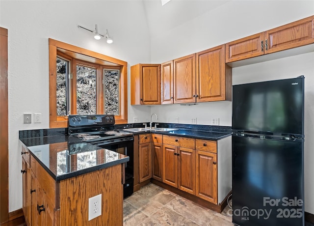 kitchen featuring brown cabinetry, dark stone counters, a peninsula, a sink, and black appliances