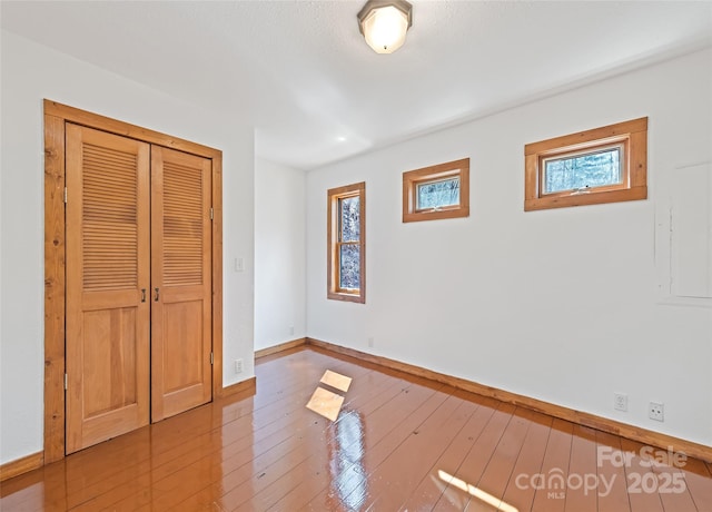 unfurnished bedroom with a closet, baseboards, and hardwood / wood-style floors