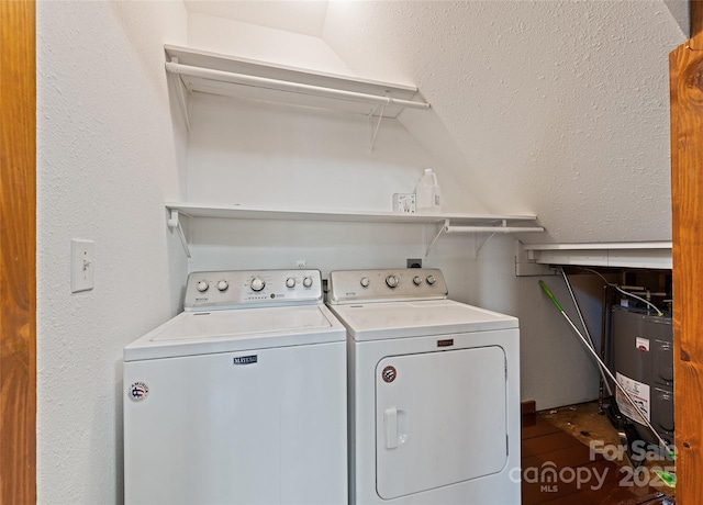 clothes washing area featuring water heater, laundry area, and washer and clothes dryer