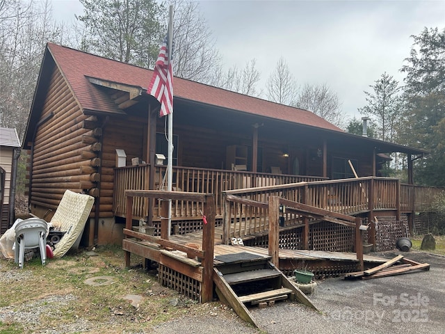 back of house featuring log exterior and a shingled roof