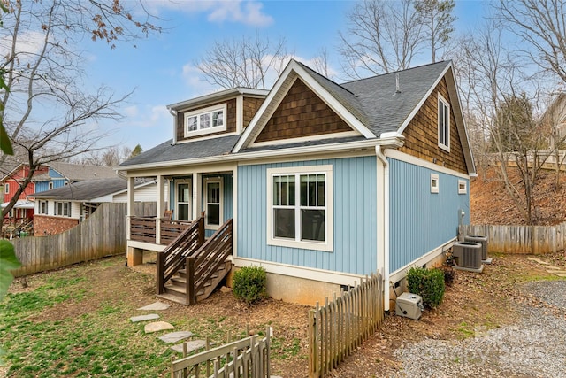 view of front of home with a porch, central AC unit, fence, and a shingled roof