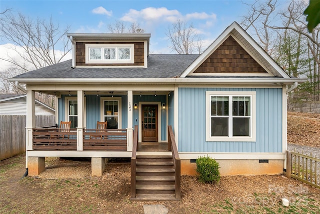 view of front of home featuring a shingled roof, fence, covered porch, and crawl space