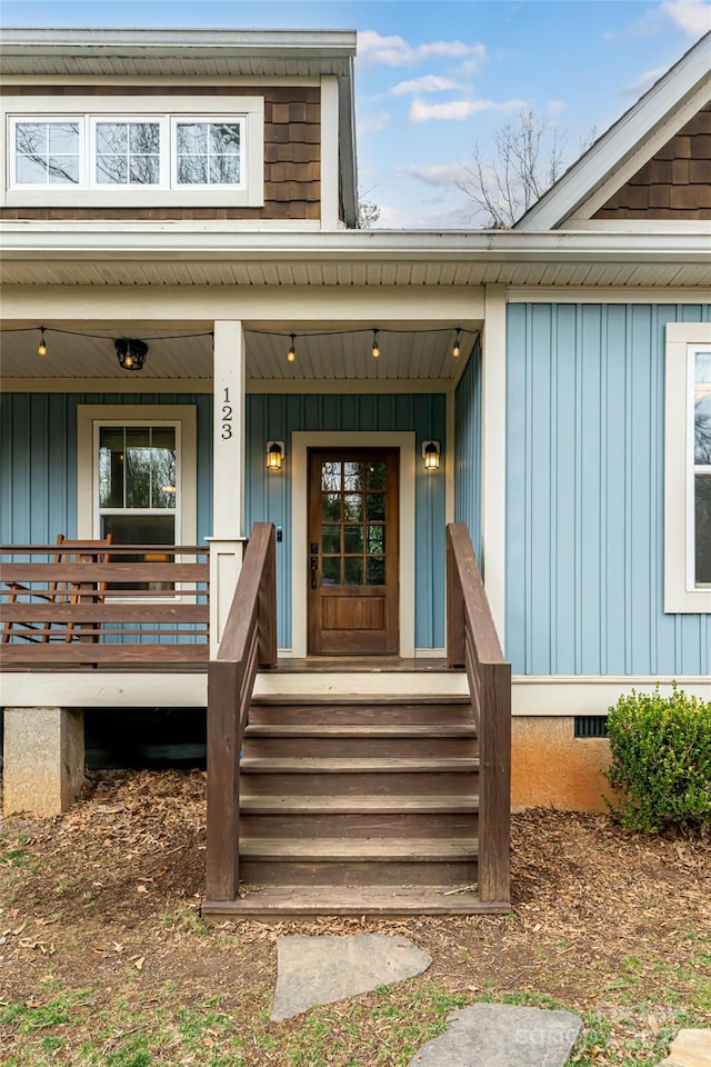 view of exterior entry with crawl space, board and batten siding, and a porch