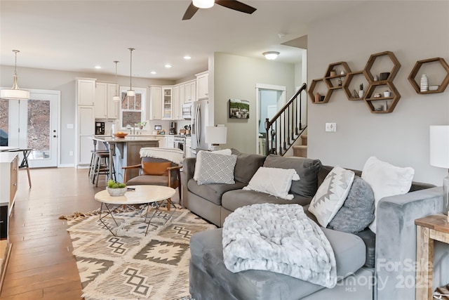 living area featuring recessed lighting, light wood-type flooring, ceiling fan, and stairs