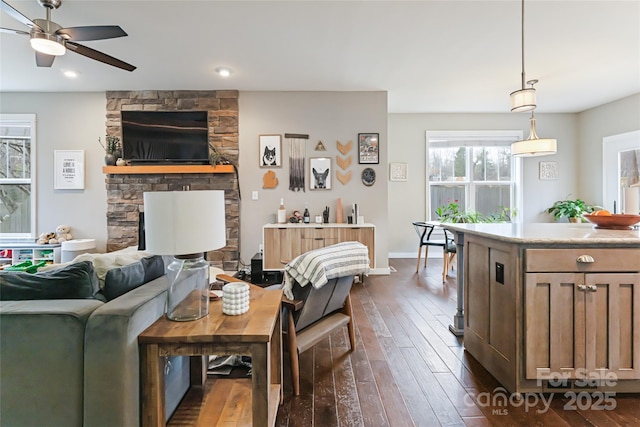 living area featuring a fireplace, ceiling fan, and dark wood-style flooring