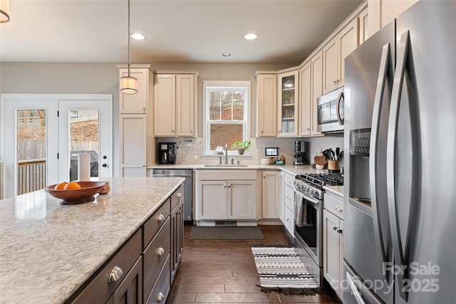 kitchen featuring cream cabinetry, a sink, stainless steel appliances, decorative backsplash, and dark wood-style flooring