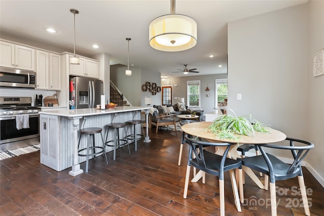 kitchen with a breakfast bar, dark wood finished floors, recessed lighting, stainless steel appliances, and light countertops