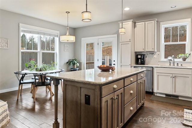 kitchen with decorative light fixtures, a sink, dark wood-type flooring, and stainless steel dishwasher