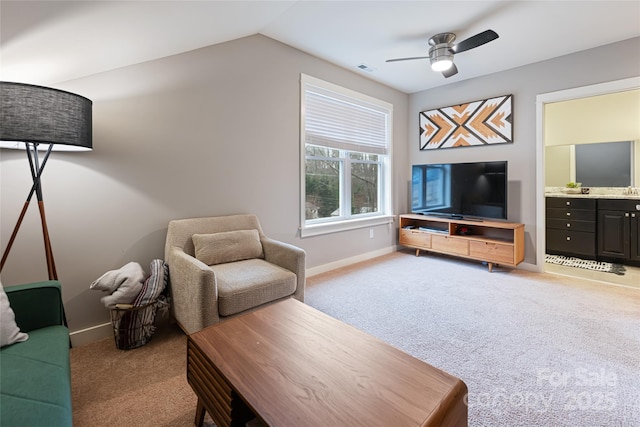 living area featuring ceiling fan, vaulted ceiling, baseboards, and light carpet