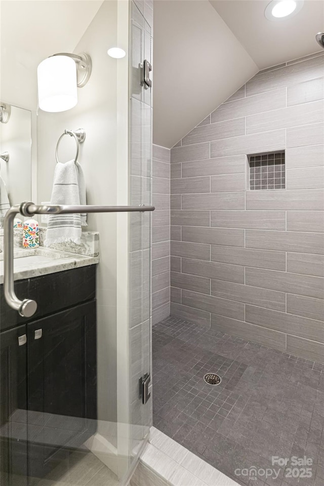 full bathroom with vanity, vaulted ceiling, and a stall shower