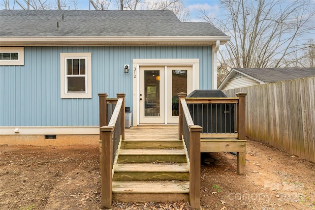 entrance to property with a shingled roof, a wooden deck, fence, and crawl space