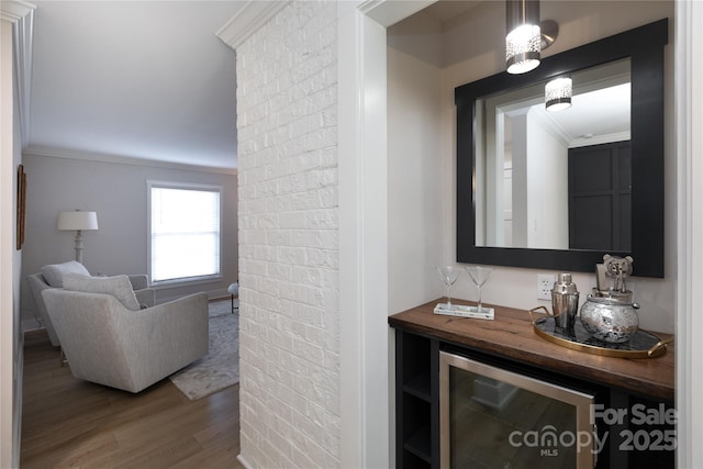 interior space with beverage cooler, brick wall, wood finished floors, and ornamental molding