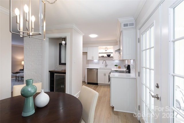 dining space with crown molding, a notable chandelier, light wood-style floors, and visible vents