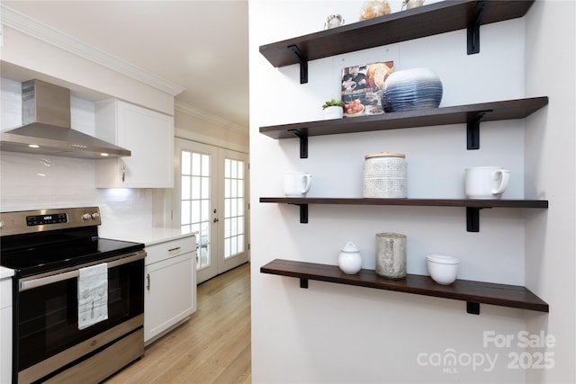 kitchen featuring open shelves, wall chimney exhaust hood, crown molding, and stainless steel range with electric cooktop