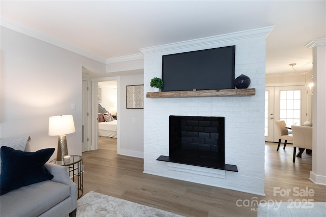 living room with wood finished floors, ornamental molding, and a fireplace