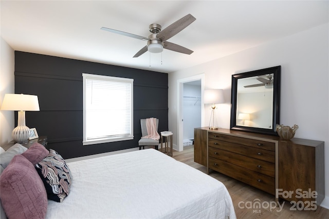 bedroom featuring a closet, a spacious closet, wood finished floors, and a ceiling fan