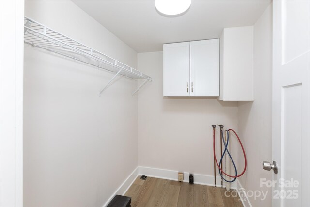 laundry area with cabinet space, hookup for a washing machine, baseboards, and light wood-style floors