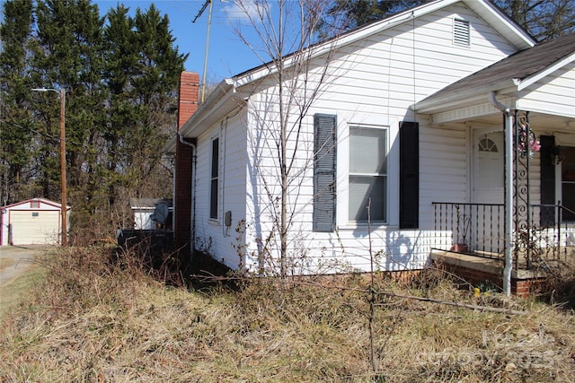 view of side of home with an outdoor structure and a chimney