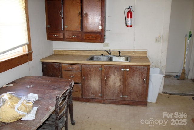 kitchen with light floors, light countertops, brown cabinets, and a sink