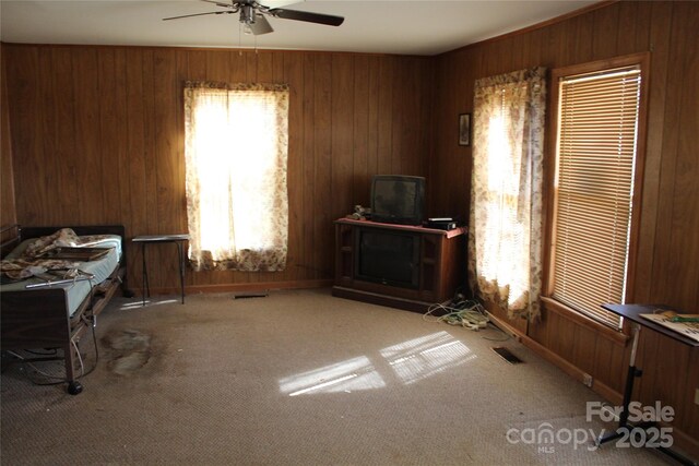 interior space featuring visible vents, wooden walls, and a ceiling fan