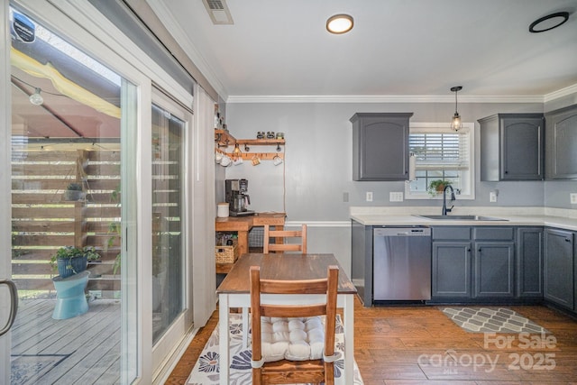 kitchen with visible vents, a sink, stainless steel dishwasher, crown molding, and light wood finished floors