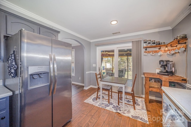 dining space with visible vents, ornamental molding, arched walkways, wood-type flooring, and baseboards