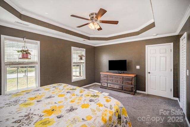 carpeted bedroom featuring ceiling fan, a tray ceiling, visible vents, and ornamental molding