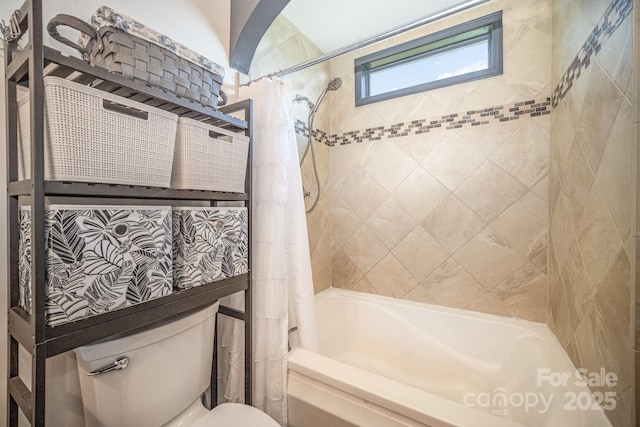 bathroom featuring toilet and shower / tub combo with curtain