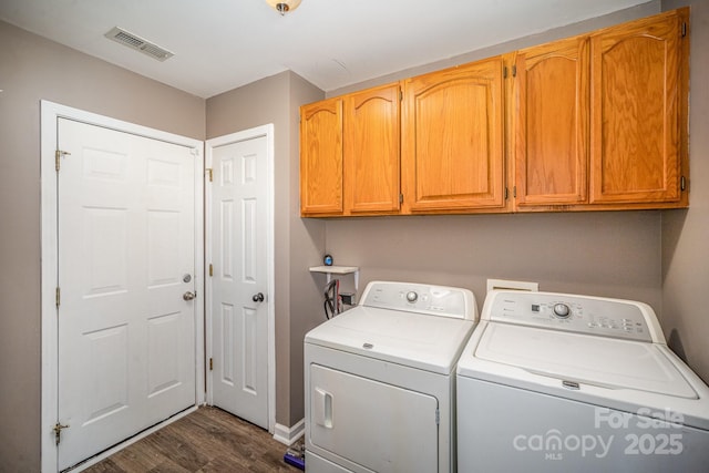 laundry room with visible vents, cabinet space, dark wood finished floors, and washer and clothes dryer