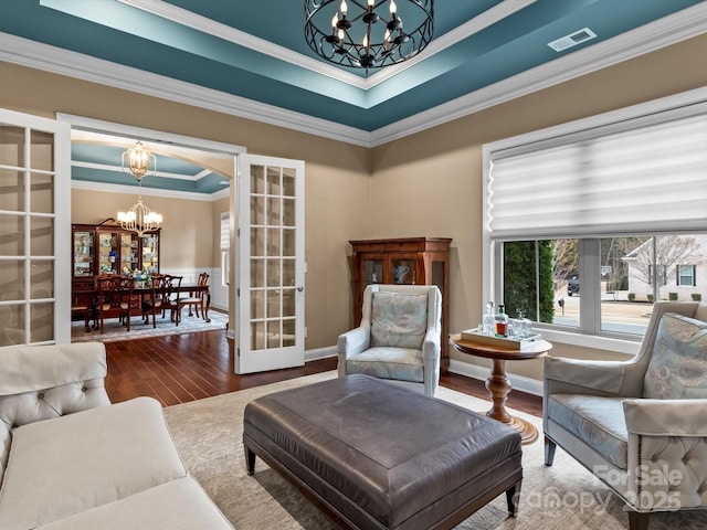 living room featuring visible vents, a notable chandelier, wood finished floors, french doors, and crown molding