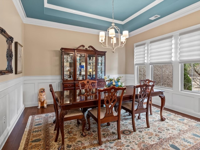 dining room with visible vents, a wainscoted wall, a tray ceiling, a notable chandelier, and wood-type flooring