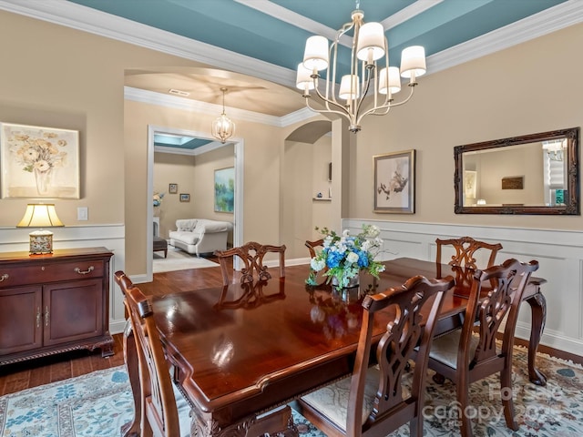 dining area with arched walkways, a notable chandelier, wainscoting, and dark wood-style floors