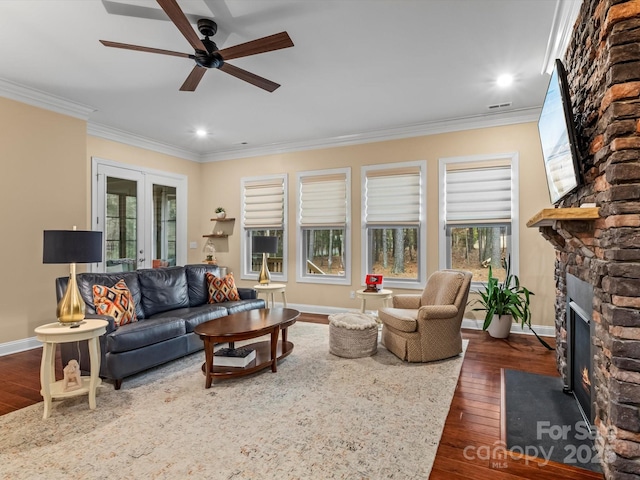 living area with a stone fireplace, crown molding, french doors, and dark wood finished floors