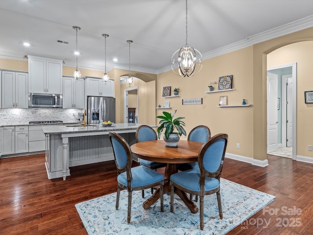 dining room featuring visible vents, dark wood-type flooring, baseboards, ornamental molding, and arched walkways