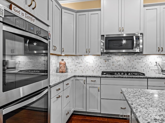 kitchen featuring light stone counters, dark wood-style floors, tasteful backsplash, and stainless steel appliances