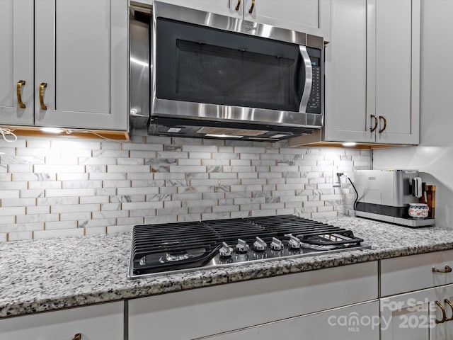 kitchen featuring stainless steel appliances, light stone countertops, and tasteful backsplash