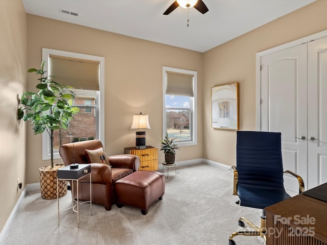 living area featuring carpet flooring, visible vents, a ceiling fan, and baseboards